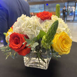 Red, yellow, and white roses in a clear square vase
