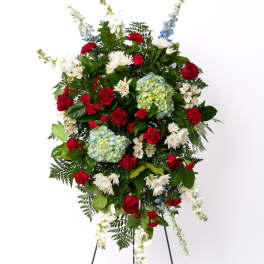 Tall red, white, and blue standing spray with roses, hydrangeas, and mums on a metal easel