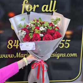 Bouquet of red roses with small white filler flowers in gray wrap