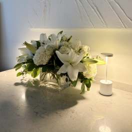 White lilies and hydrangeas in a clear glass vase