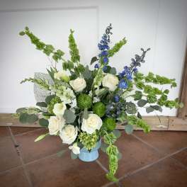 White roses and blue delphinium in a light blue vase