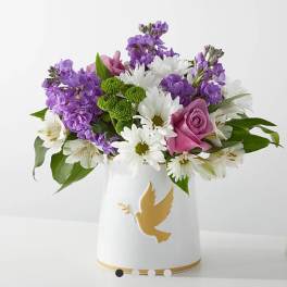 Purple and white bouquet in a white vase with a gold dove design