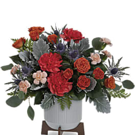 Arrangement of red and orange roses in a white vase