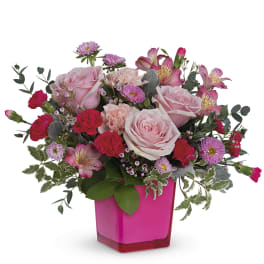 Pink roses and mixed flowers in a bright pink vase