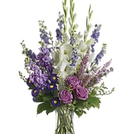 Tall bouquet of purple and white flowers in a clear glass vase
