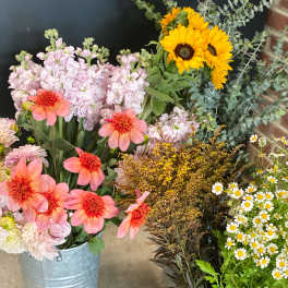 Mixed flower arrangements in metal buckets with sunflowers and pink blooms