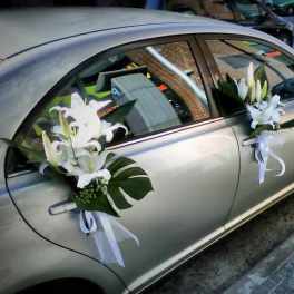 White lilies with ribbons attached to a silver car