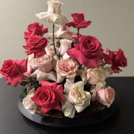 Arrangement of pink and red roses in a low round container