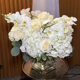 White orchids and roses arranged in a square glass vase