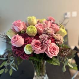 Pink roses and carnations arranged in a clear glass vase