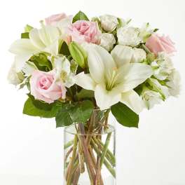 Pink and white bouquet of roses and lilies in a clear glass vase