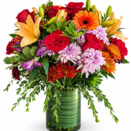 Mixed bouquet of roses, lilies, and chrysanthemums in a green glass vase