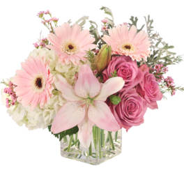 Pink gerberas, roses, and a lily in a clear glass vase