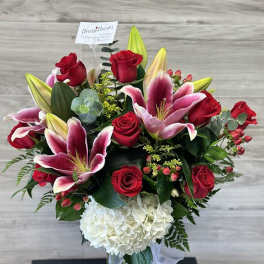 Bouquet of red roses, pink lilies, and white hydrangea in a glass vase