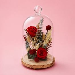 Red roses and dried flowers under a glass dome on a wooden base