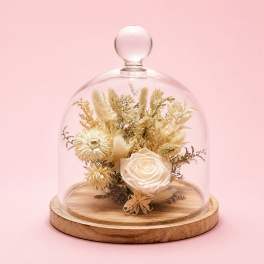 Dried floral arrangement under a glass dome on a wooden base