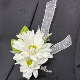 White daisy boutonniere with silver ribbon on a dark suit jacket