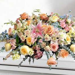 Large pastel floral arrangement with roses, lilies, and blue accents