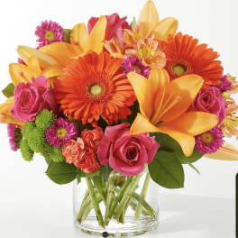 Bright mixed bouquet in a clear glass vase with orange lilies and pink roses