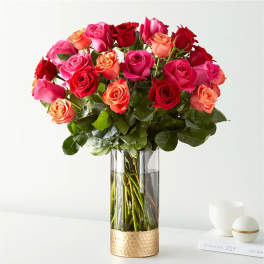 Bouquet of pink, red, and peach roses in a tall glass vase