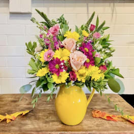 Mixed pink and yellow bouquet in a yellow pitcher vase