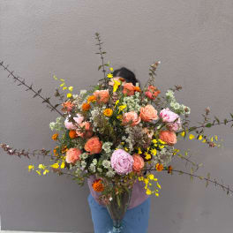 Large mixed bouquet with peach and pink roses in a clear vase