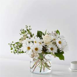 White daisies and a cream rose in a clear glass vase