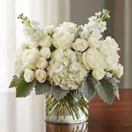White roses and hydrangeas in a clear glass vase