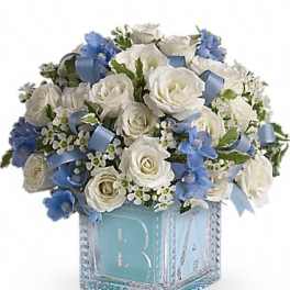 White roses and blue flowers in a decorative cube vase