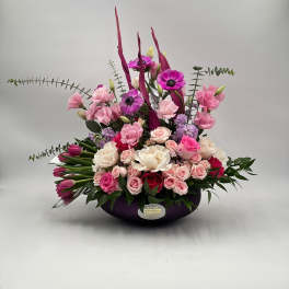 Pink and white floral arrangement in a dark bowl vase
