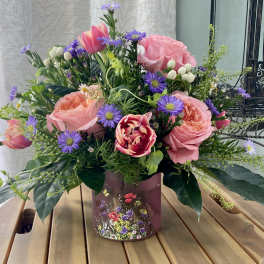 Pink roses and tulips with purple daisies in a decorative vase