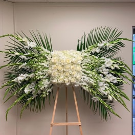 Large white floral spray with roses and lilies on an easel