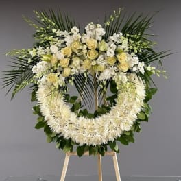 Large white floral wreath on a wooden stand