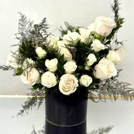 Arrangement of white roses with airy greenery in a tall black cylinder vase