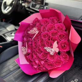 Bouquet of hot pink roses wrapped in pink paper with butterfly decorations