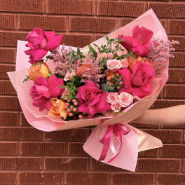Pink rose bouquet wrapped in pale pink paper with a ribbon