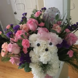 Pink and white floral arrangement with a teddy bear centerpiece