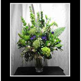 Tall green and white floral arrangement in a clear glass vase