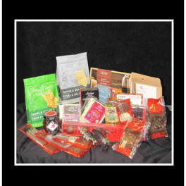 Assorted gourmet snack and candy gift basket on black fabric