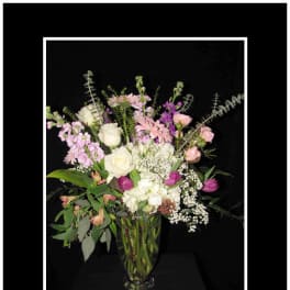 Mixed pink and white flowers arranged in a clear glass vase