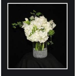 White floral arrangement in a clear vase with a glittery base