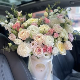 Large bouquet of pale pink, white, and cream roses in a white box