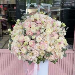Large pastel bouquet of pink and white flowers in a tall white pedestal vase