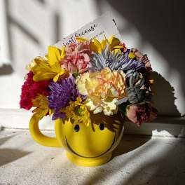 Colorful mixed bouquet in a yellow smiley-face mug
