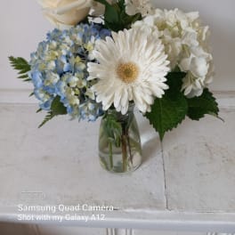 White and blue flower arrangement in a glass vase