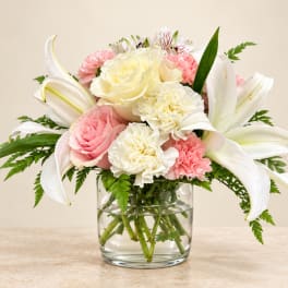 Pink and white bouquet with lilies, roses, and carnations in a glass vase