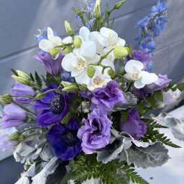 Bouquet of white orchids and purple flowers with silver foliage