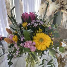 Mixed bouquet in a clear glass vase with yellow and pink blooms