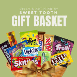 Candy gift basket in a wicker basket with assorted sweets and a gold bow