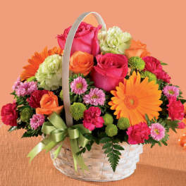 Basket arrangement of pink and orange flowers with a green ribbon